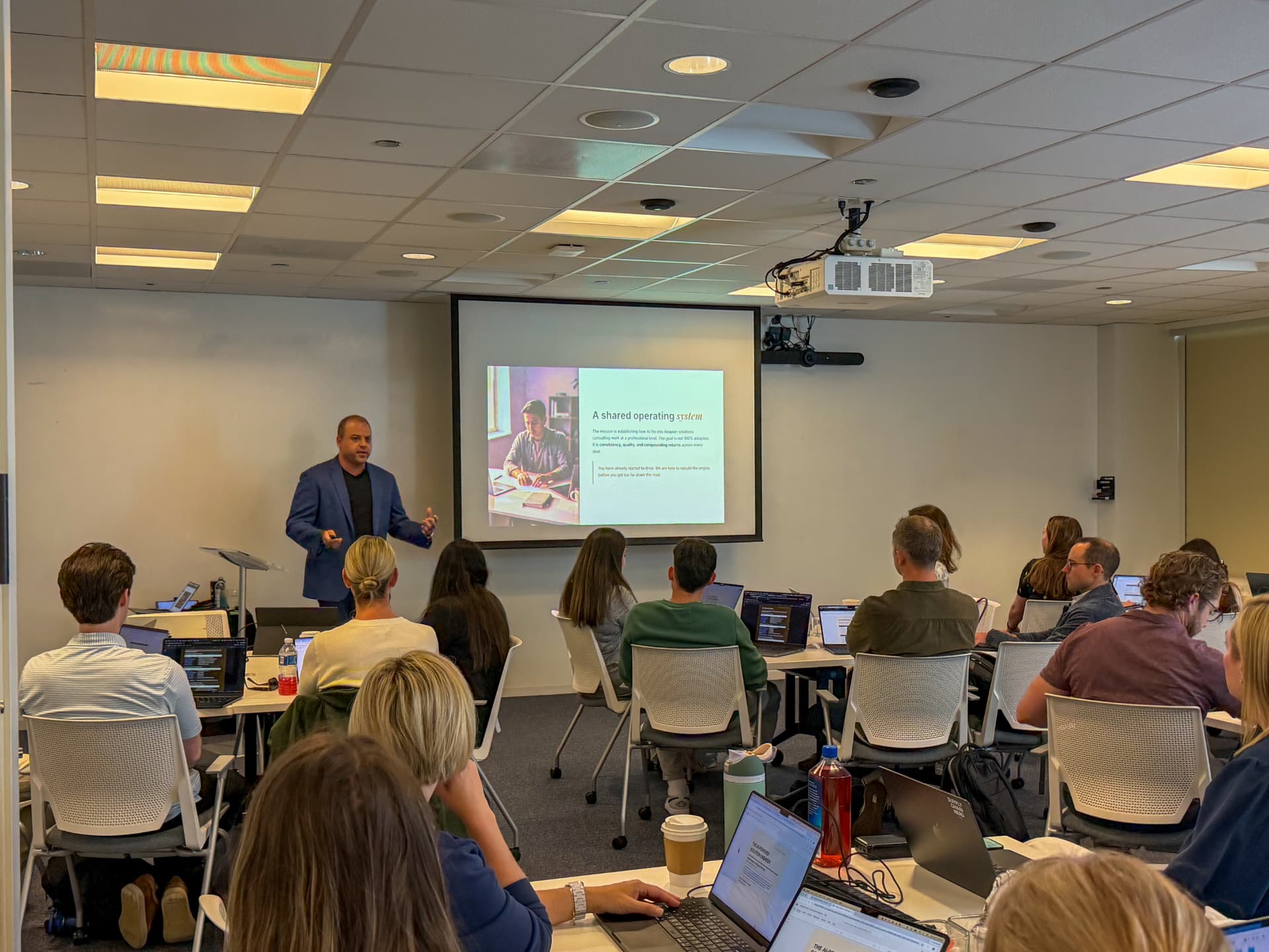 David facilitating an enablement session with a classroom of professionals at their laptops.